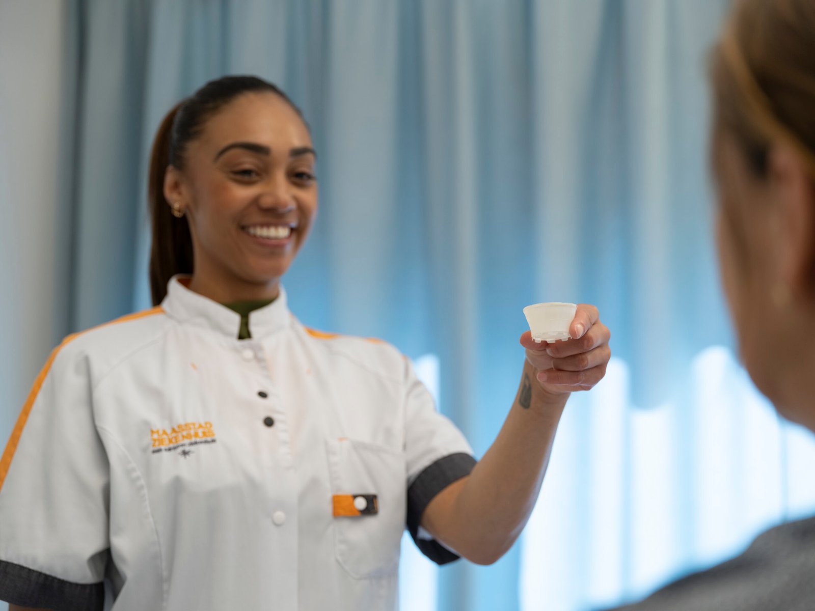 Verpleegkundige Maasstad Ziekenhuis toont het Plastilose medicijncupje aan patiënt